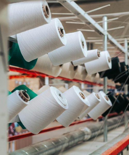 Detailed view of yarn spools in a textile factory, showcasing industrial equipment.